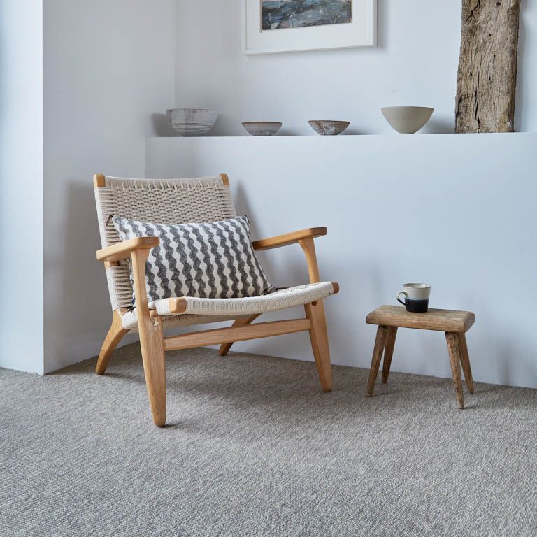 A chair with a striped pillow sits next to a small stool