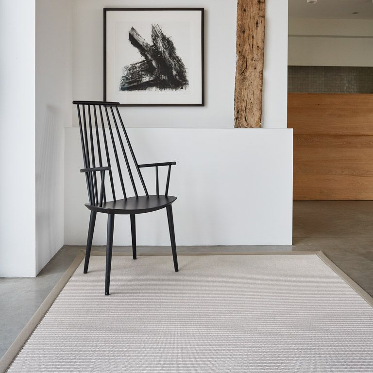 A black chair is sitting on a rug under a picture on the wall