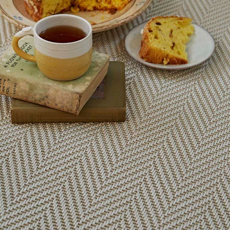 A cup of tea is sitting on top of a book next to a plate of food.