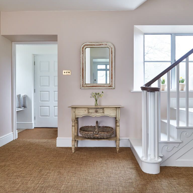 A hallway with stairs and a table with a basket on it