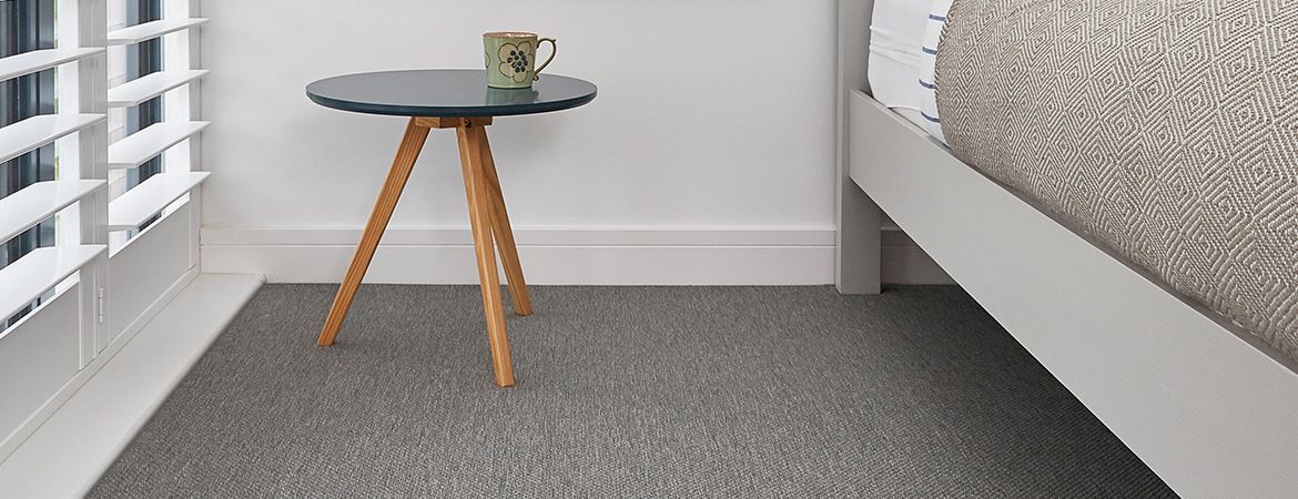 A bedroom with a bed , a table , and a rug.