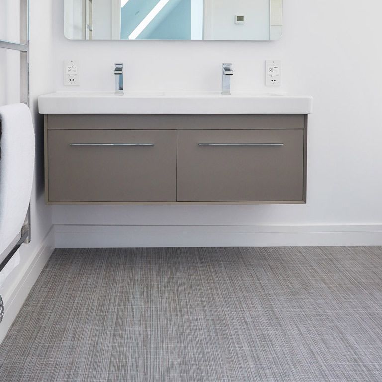 A bathroom with two sinks , a mirror , and a gray floor.