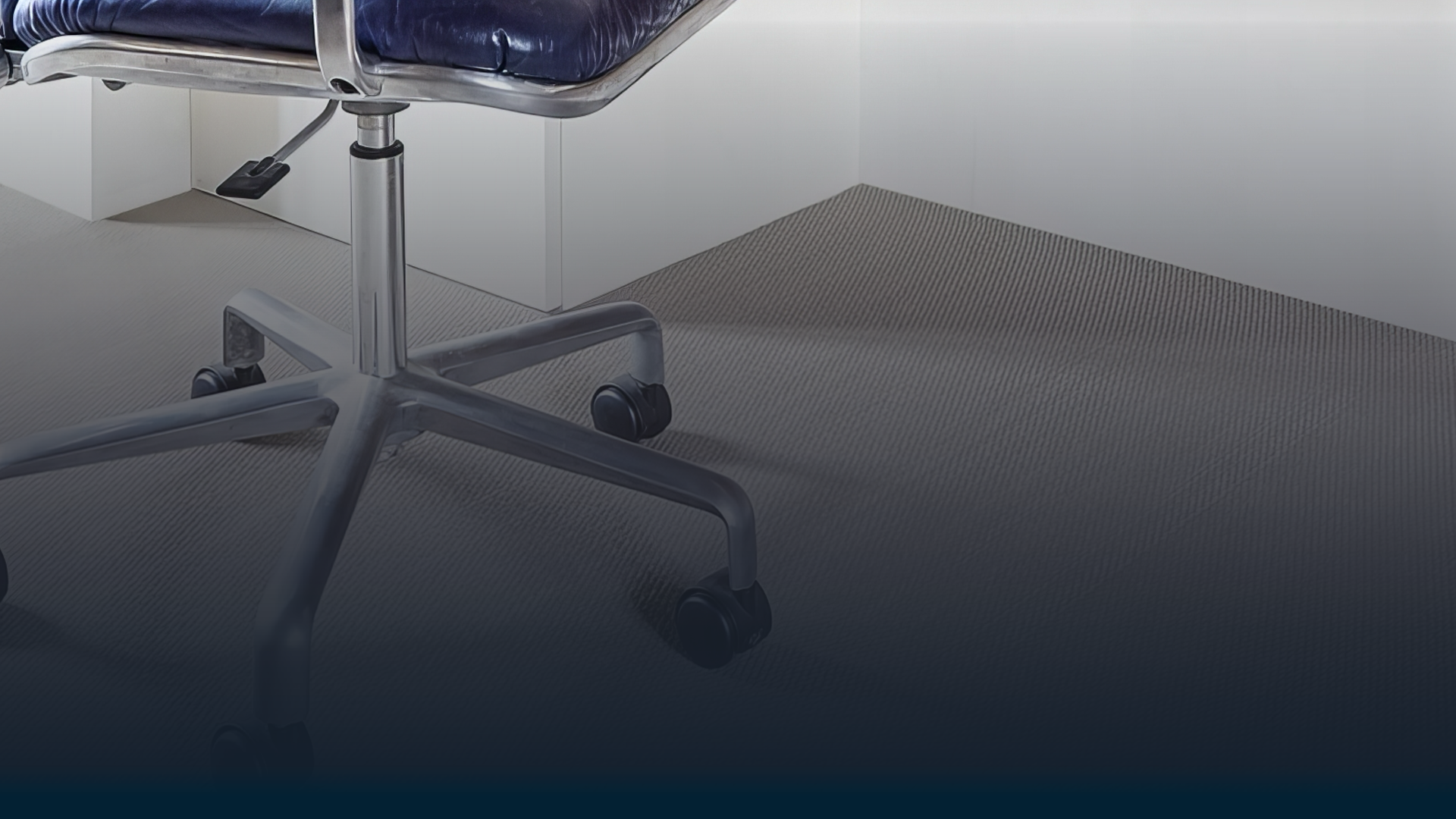 A blue office chair is sitting on a carpeted floor in a room.