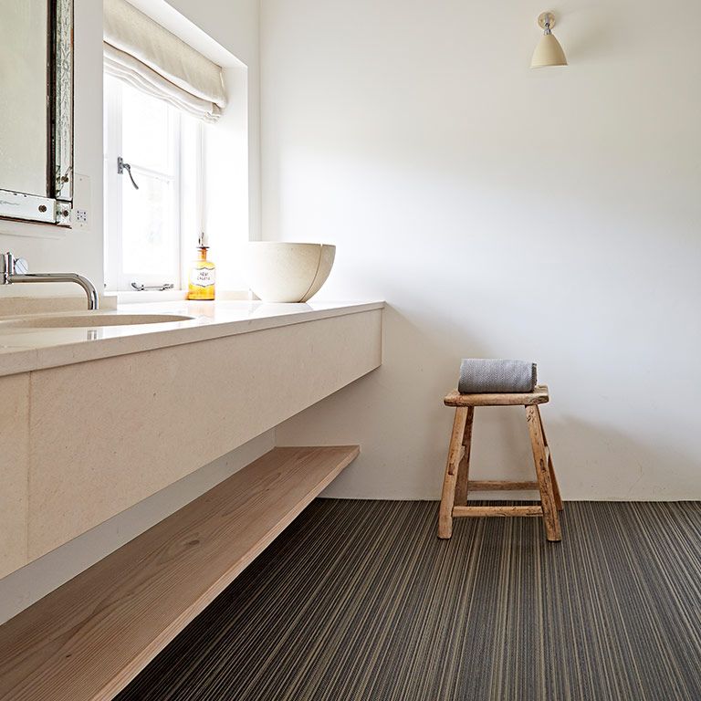 A bathroom with a sink and a stool with a towel on it