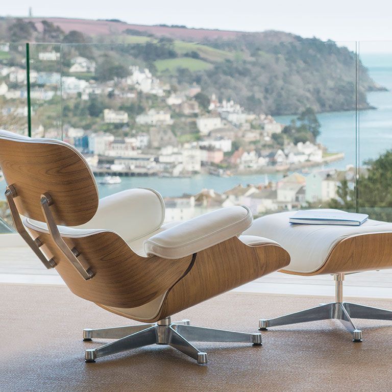 A chair and ottoman are sitting on a balcony overlooking a body of water.