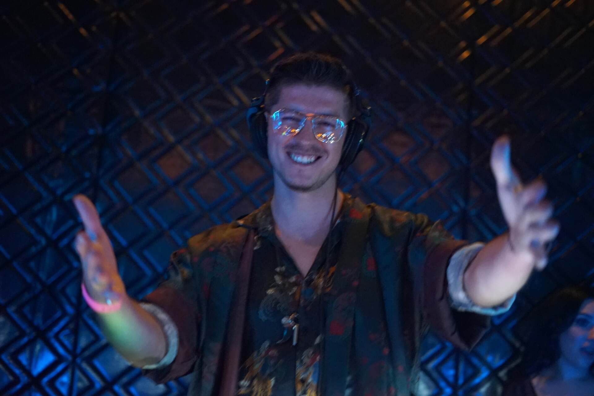 a man wearing headphones and glow in the dark glasses is dancing in a dark room .