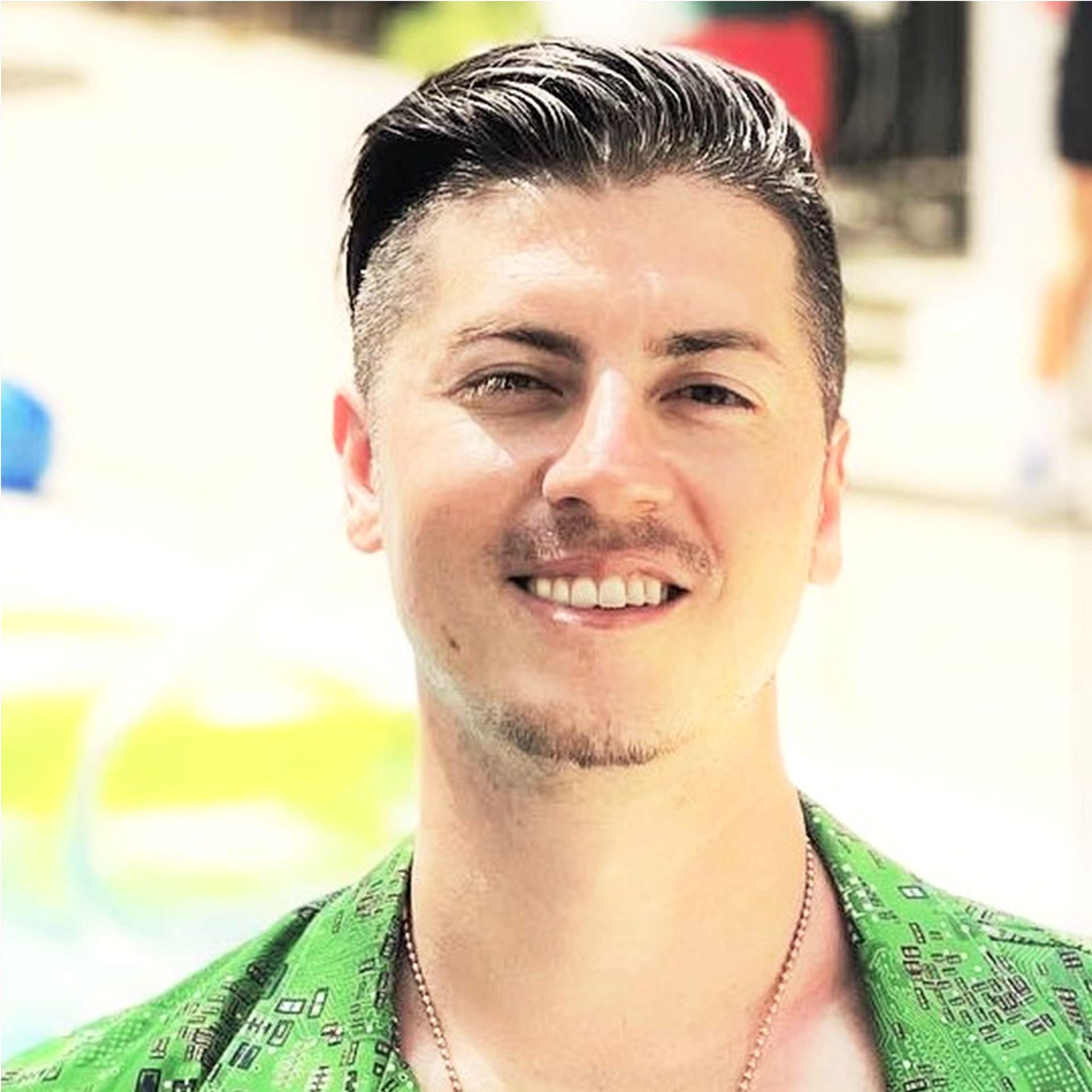 A man wearing a green shirt is smiling for the camera