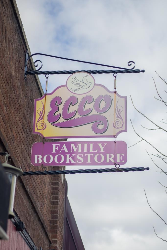 A sign for 'Ecco Family Bookstore' hangs from the side of a building.