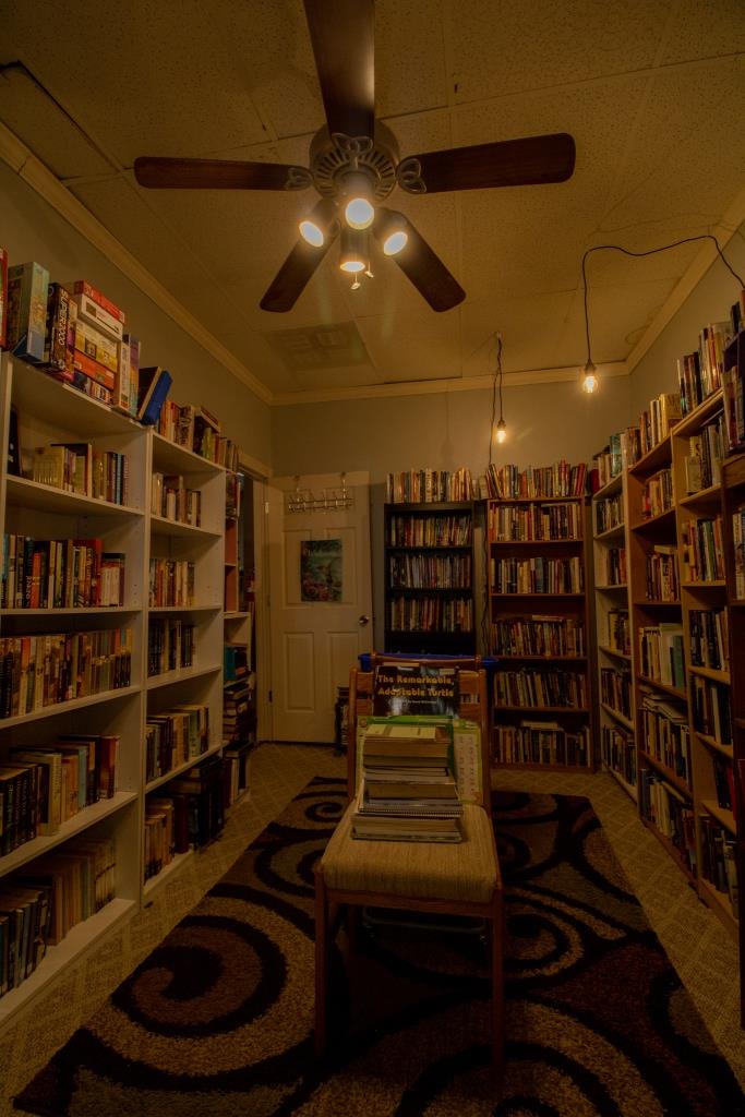 A library filled with books and a ceiling fan.