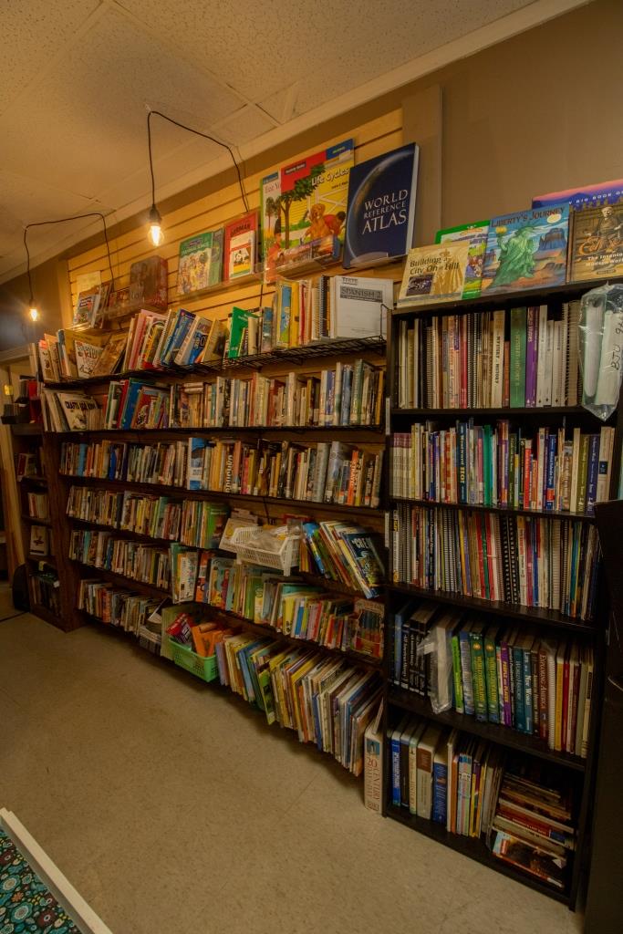 A book store filled with lots of books including a blue atlas.
