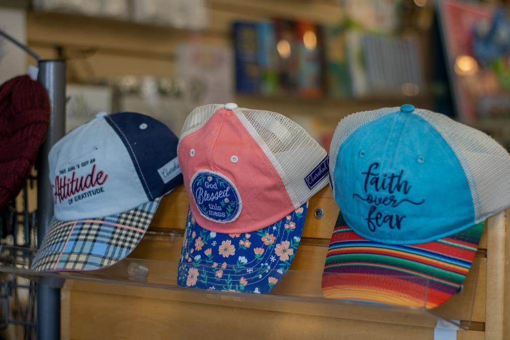 Three hats on a shelf with one that says 'faith over fear.'