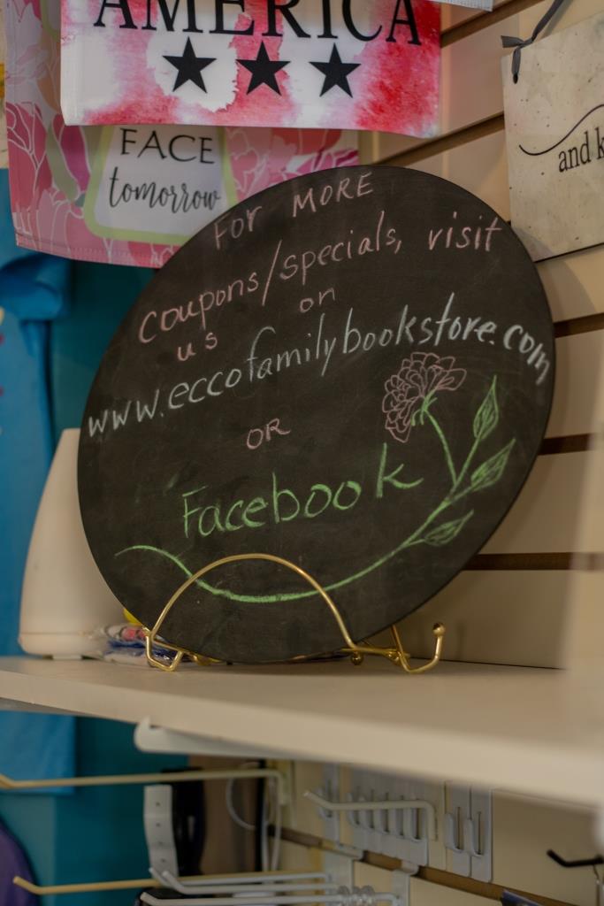 A sign on a shelf that says 'visit us on Facebook.'