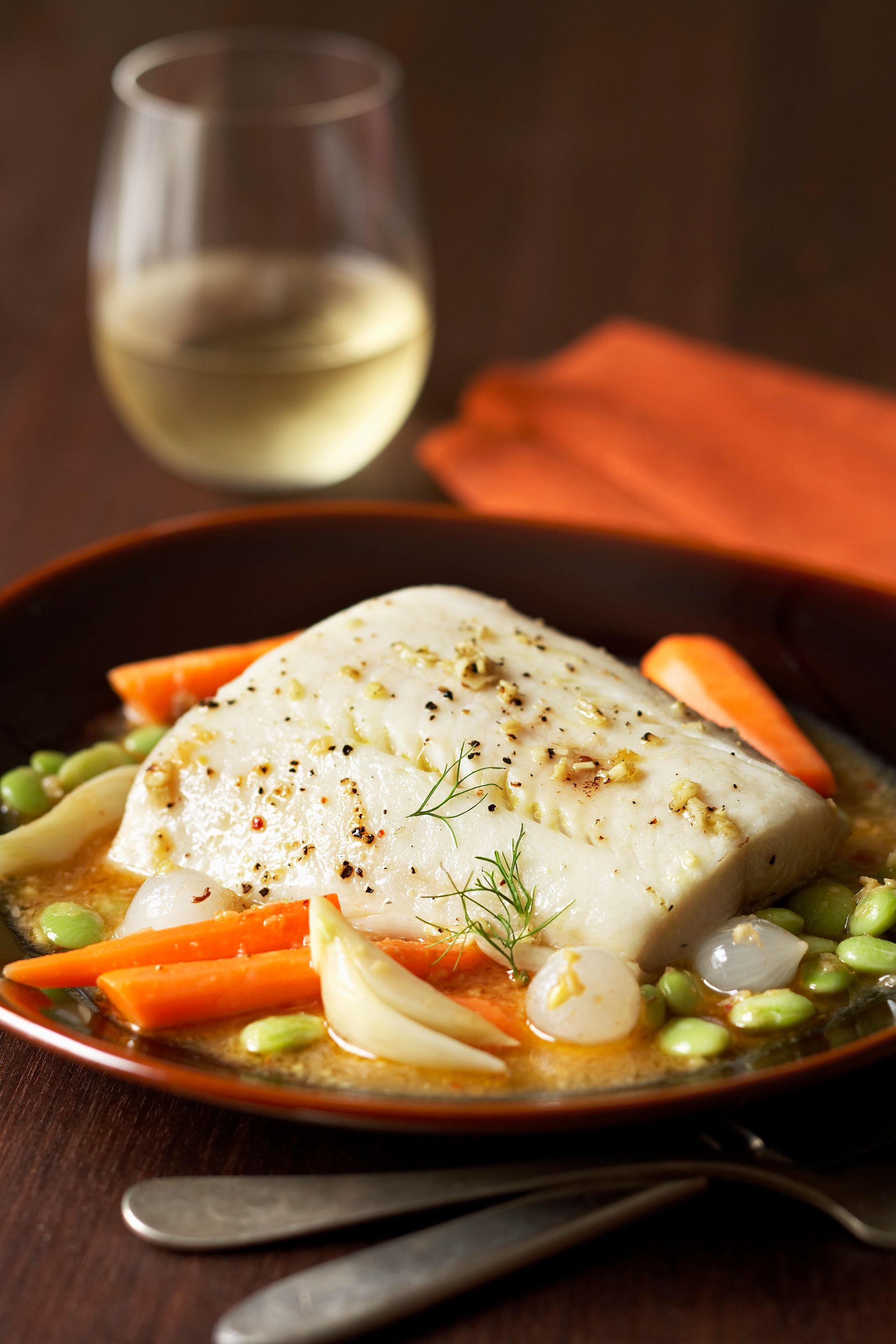 A plate of food with vegetables and a glass of wine on a table.