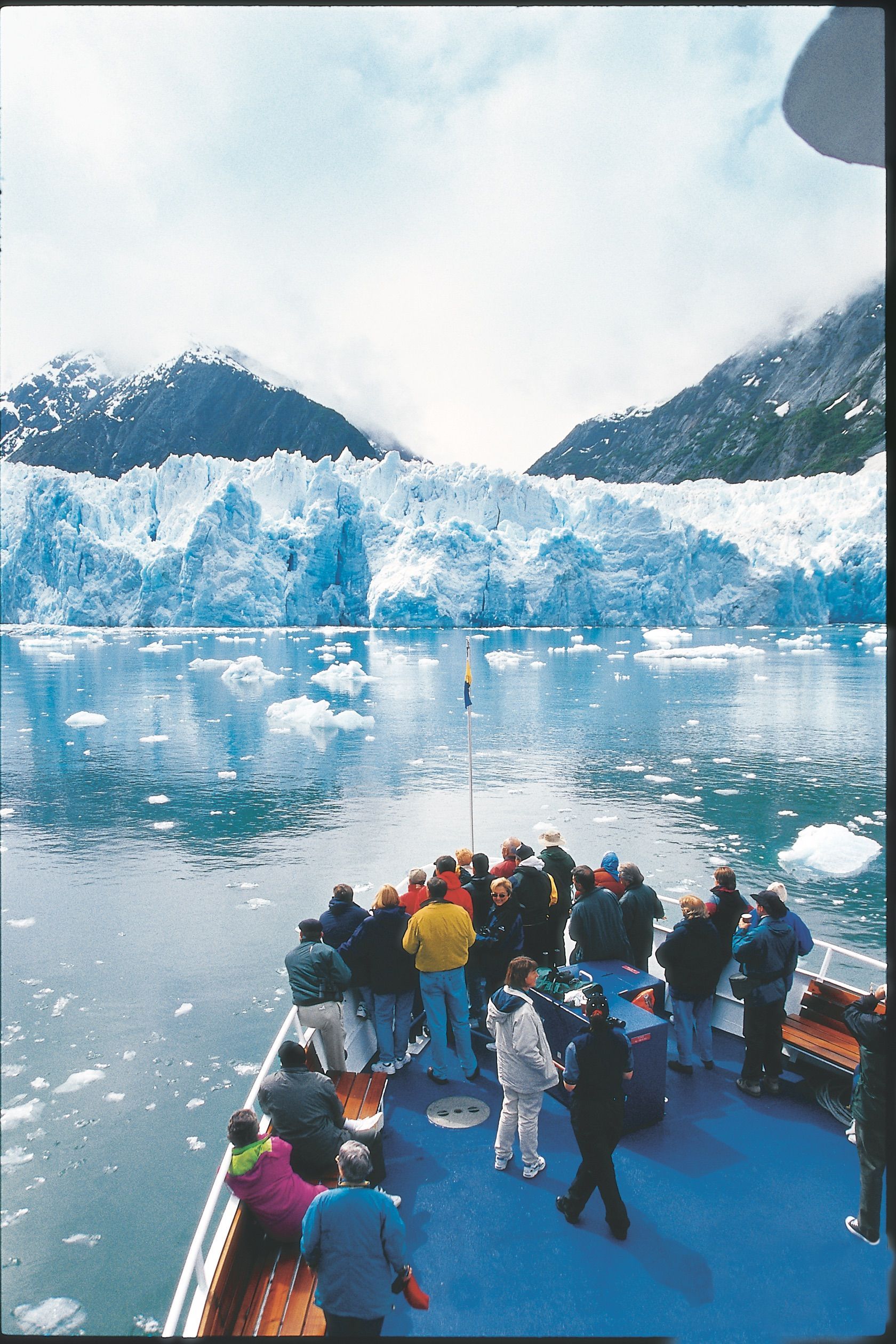 A group of people on a boat looking at a glacier