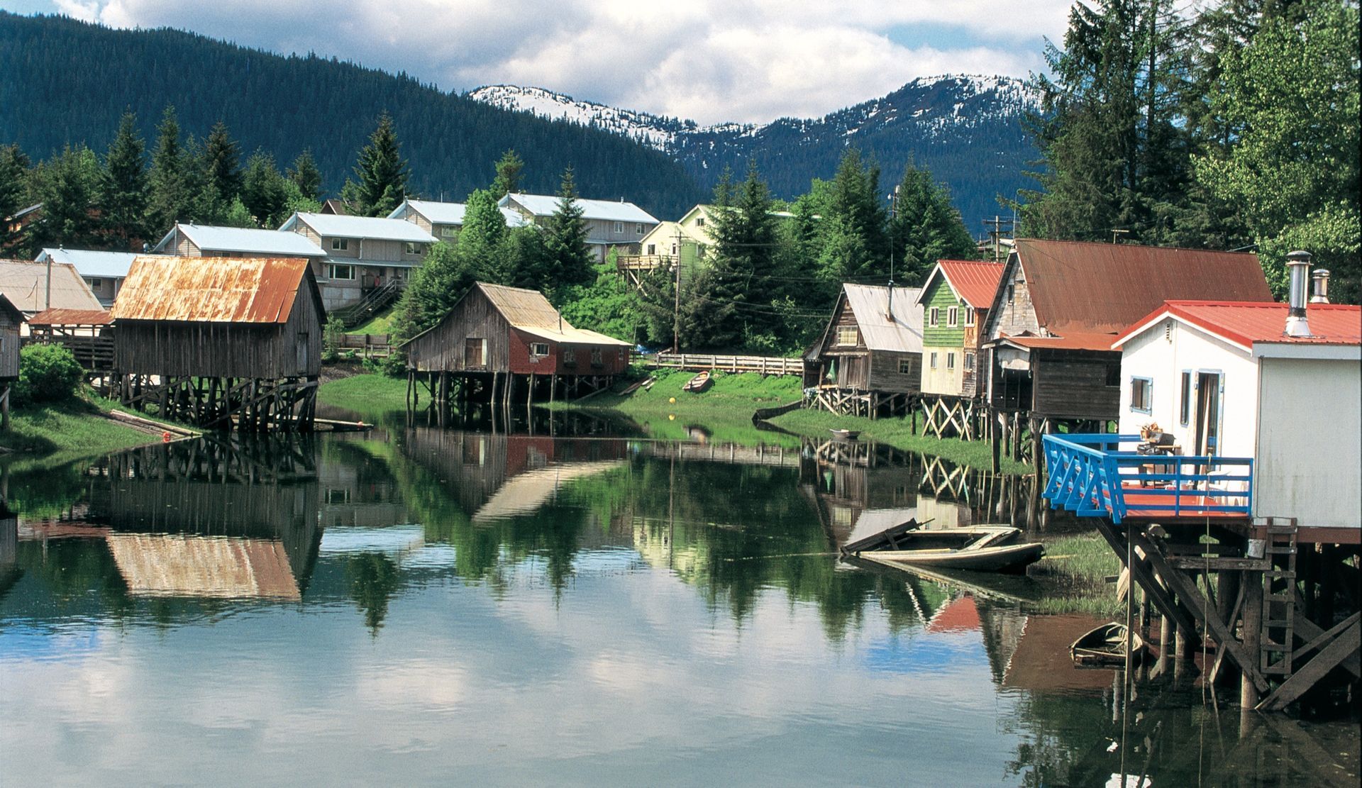 A small town sits on the shore of a lake with mountains in the background