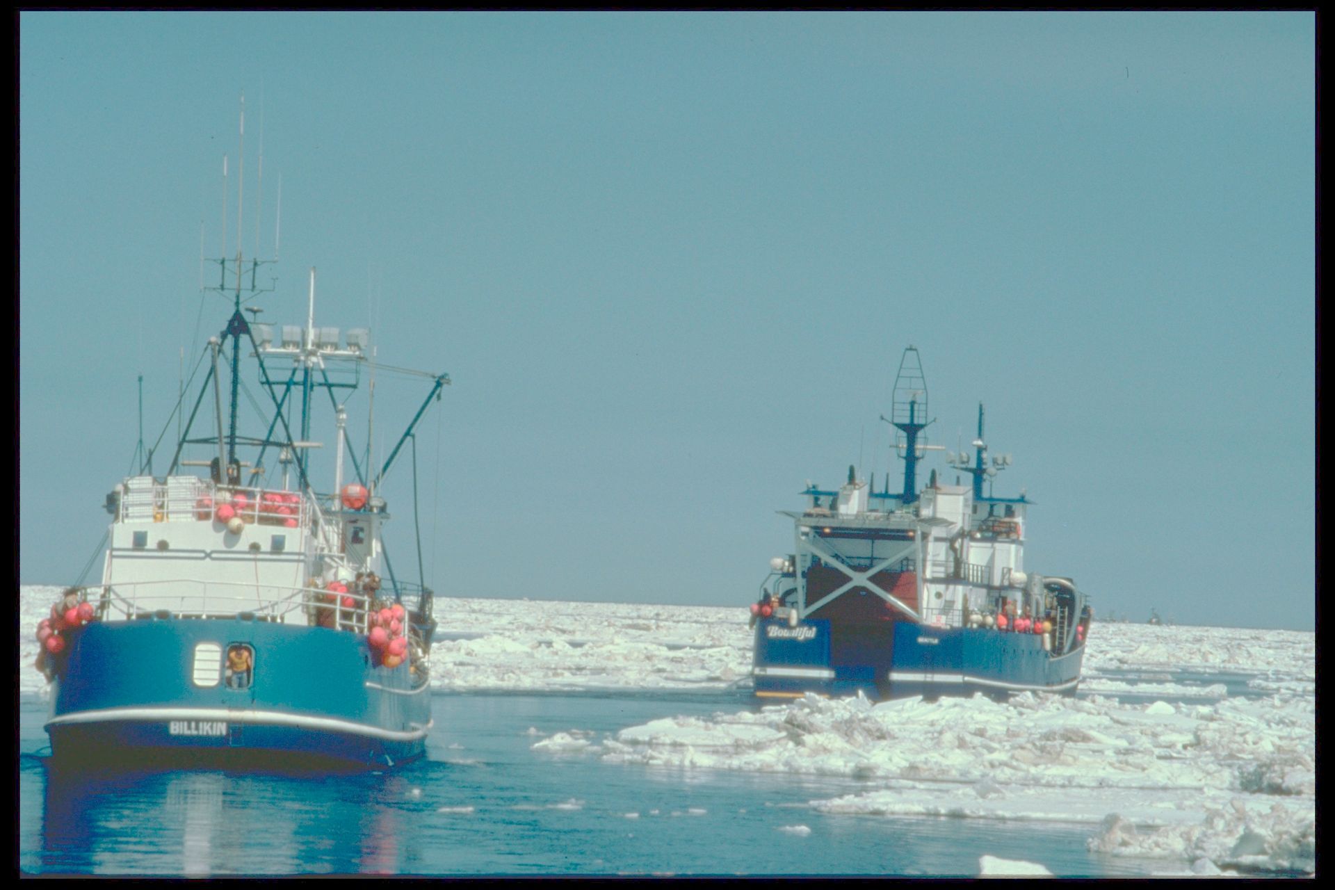 Two boats are floating on top of a body of water.