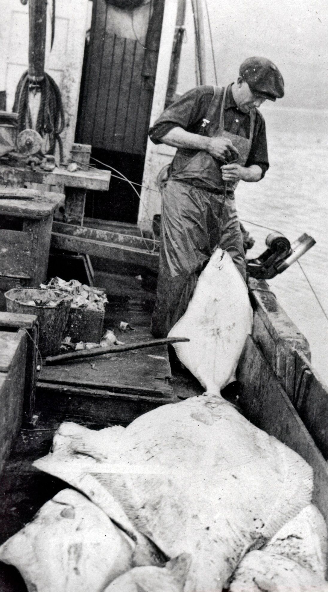 A man is standing on a boat holding a large fish.