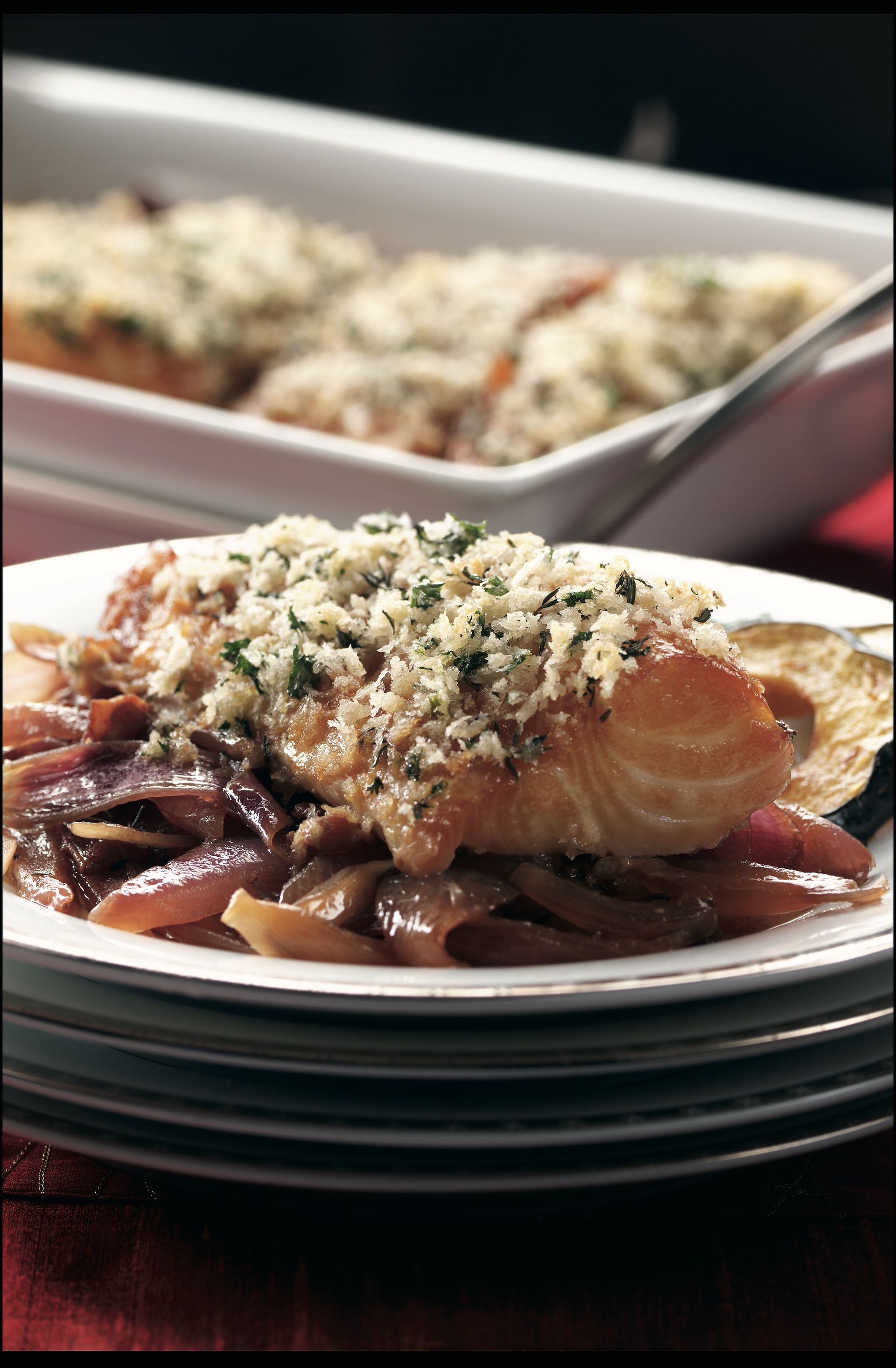 A plate of food with a casserole dish in the background