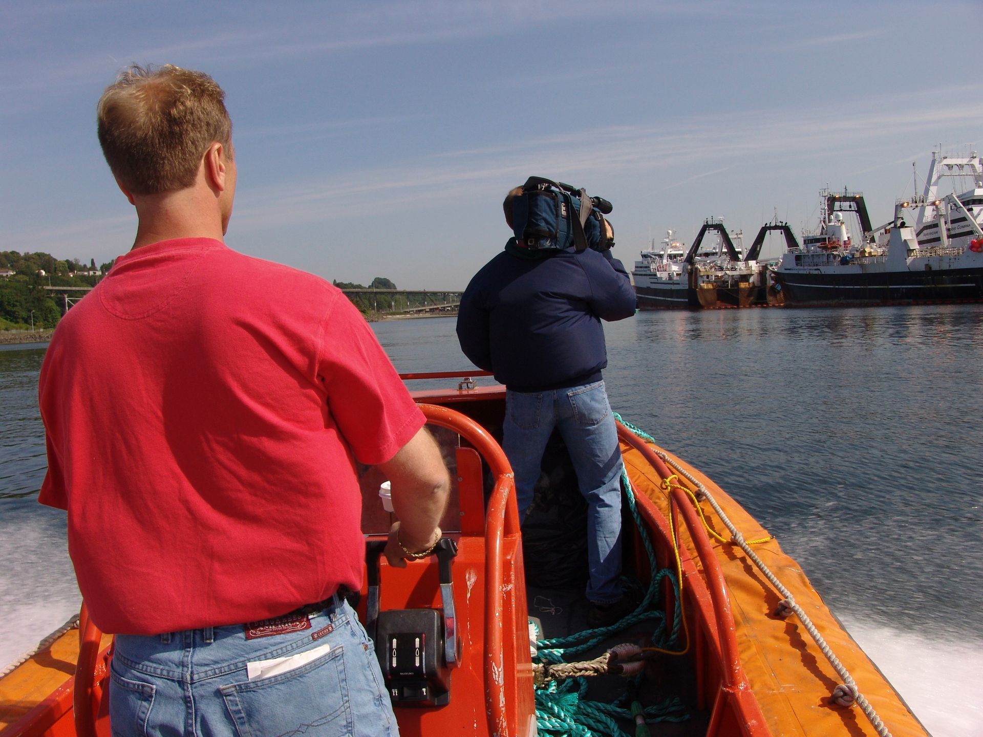 A man in a red shirt is driving a boat