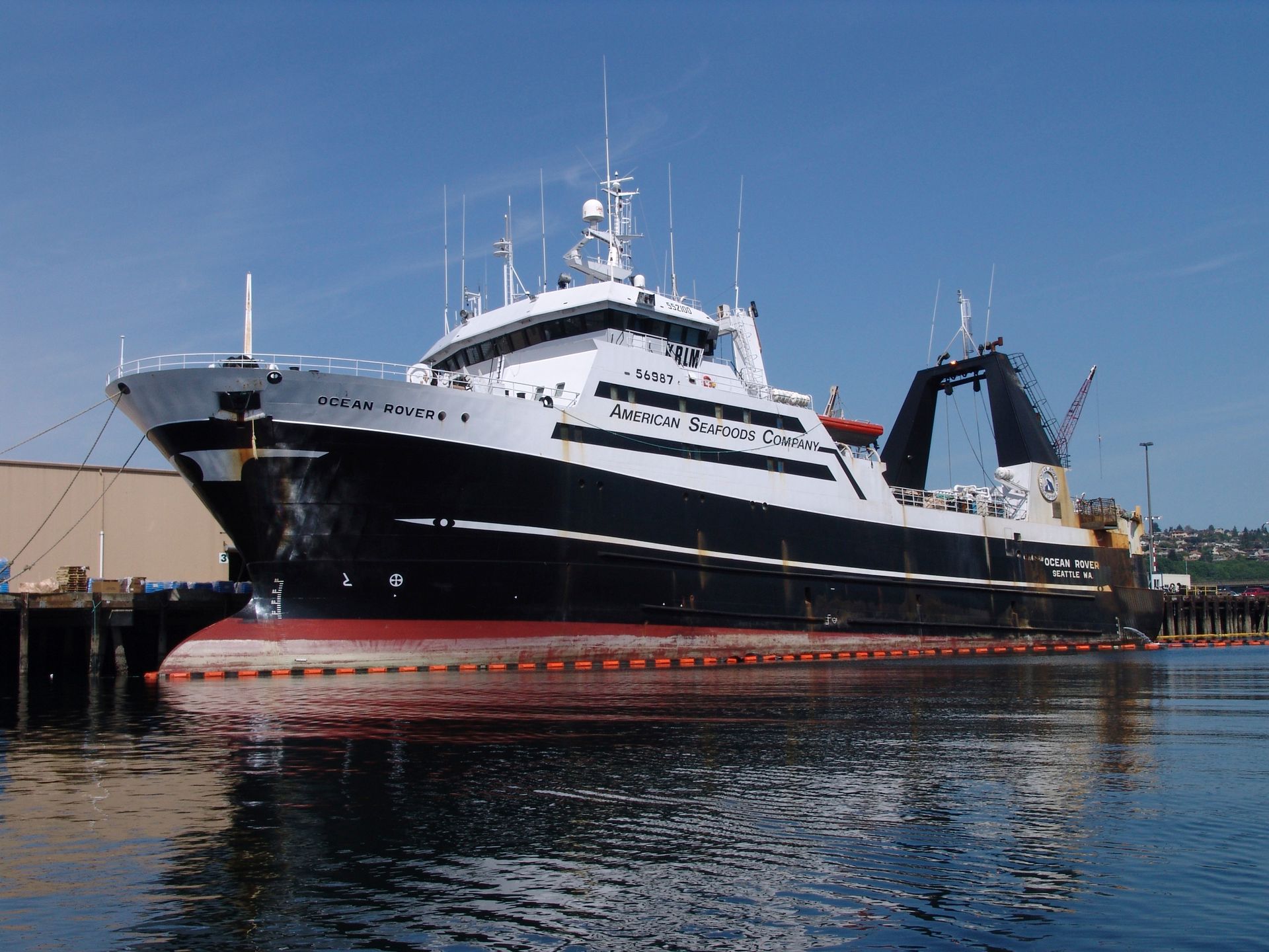 A large black and white ship is docked in a harbor