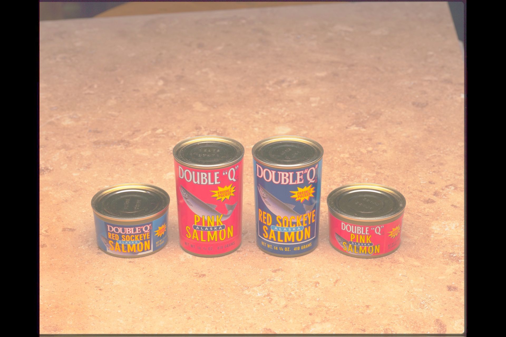 Four cans of salmon are lined up on a table