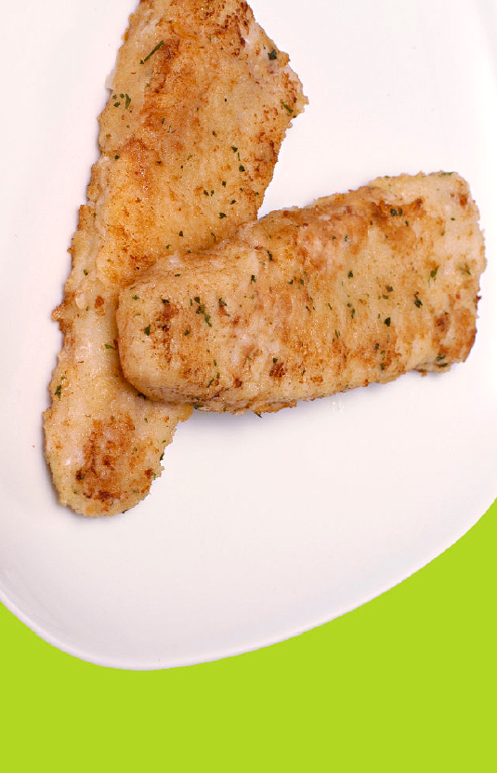 Two pieces of chicken on a white plate on a green background.