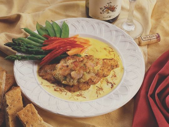 A plate of food with a bottle of wine in the background