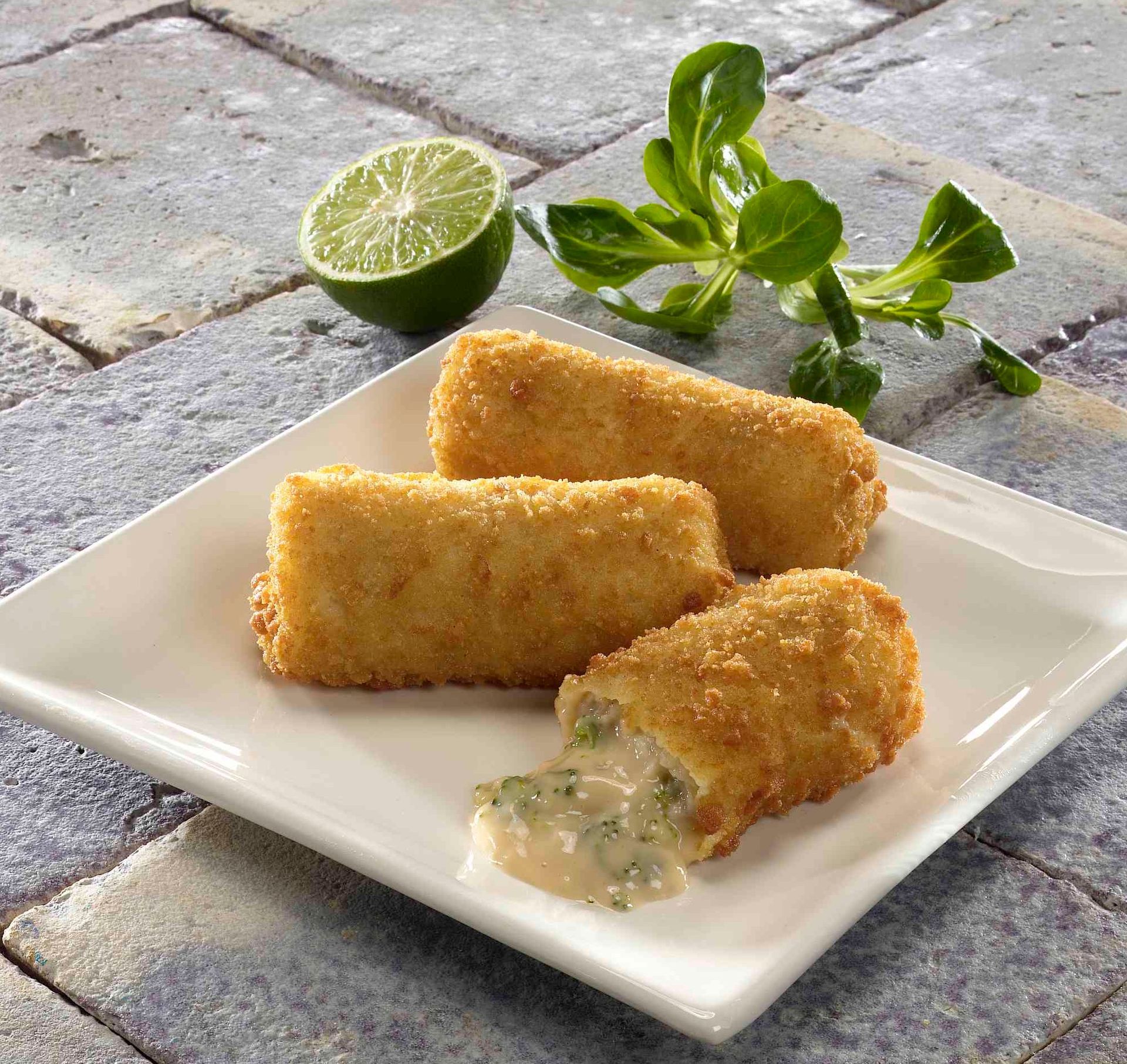 A white plate topped with fried food next to a lime