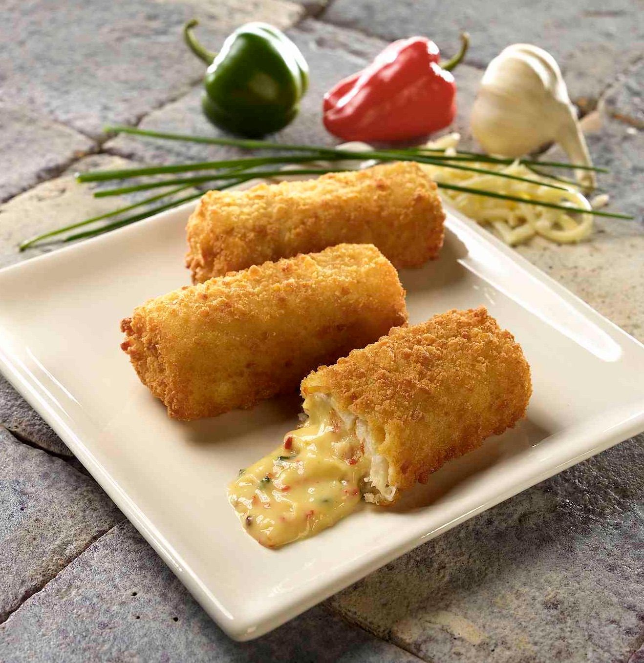 A white plate topped with fried cheese rolls with a bite taken out of one of them