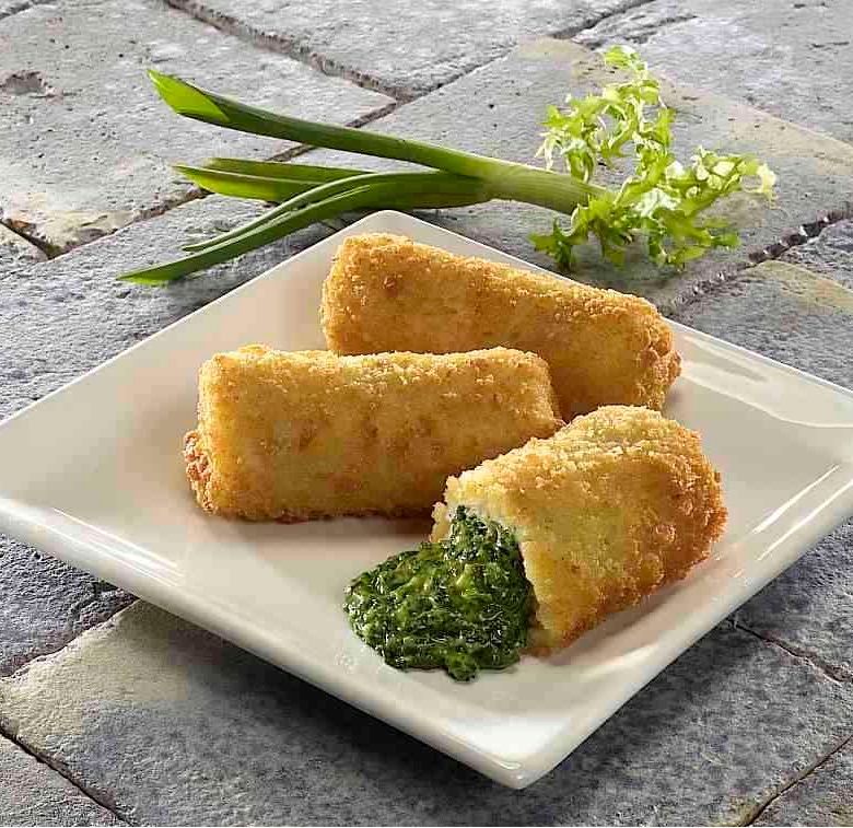 Three fried food rolls with spinach on a white plate