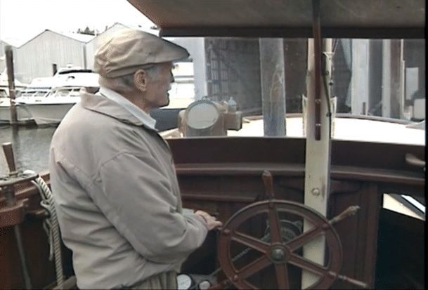 A man in a hat is steering a boat