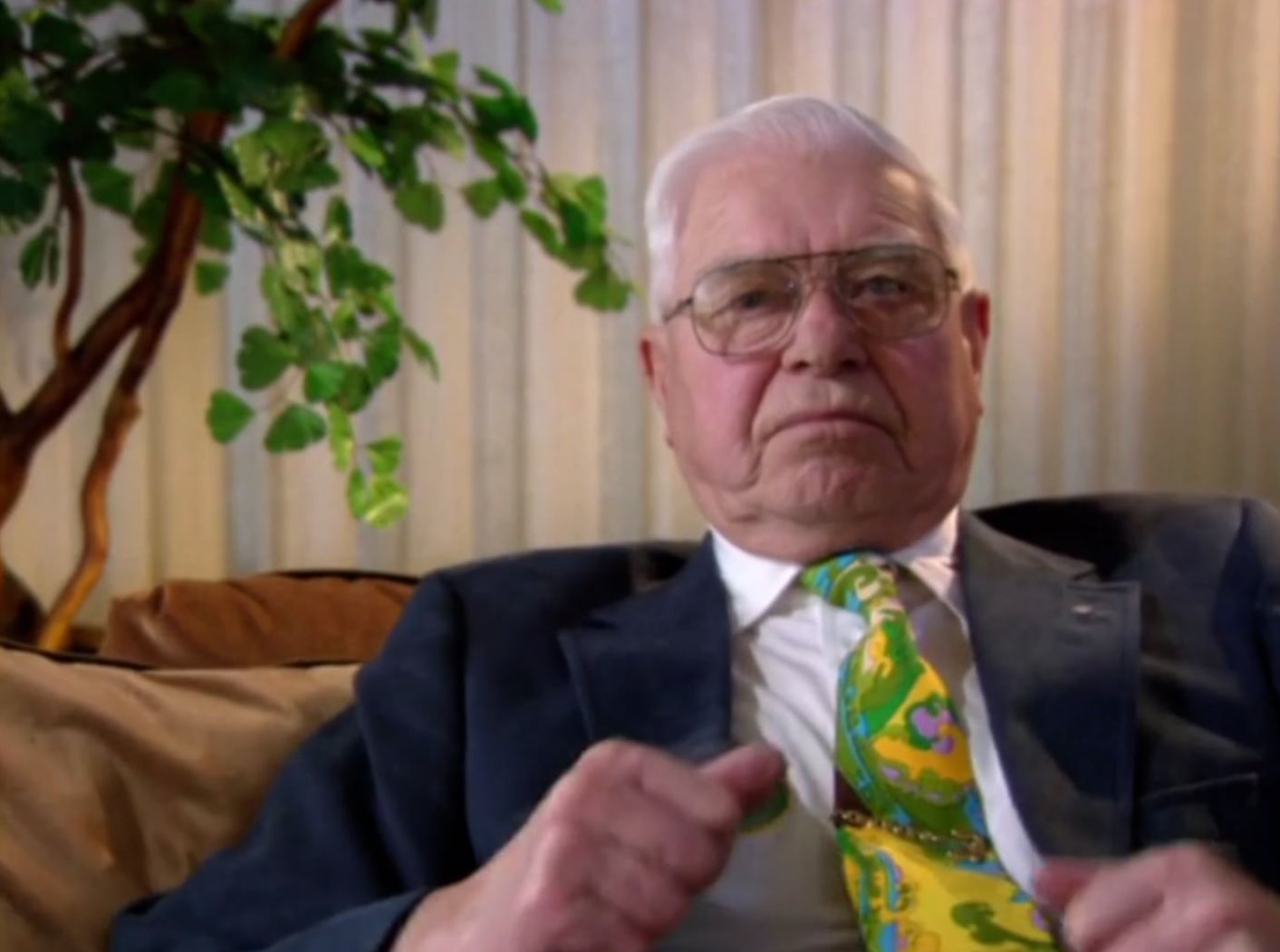 A man in a suit and tie is sitting on a couch