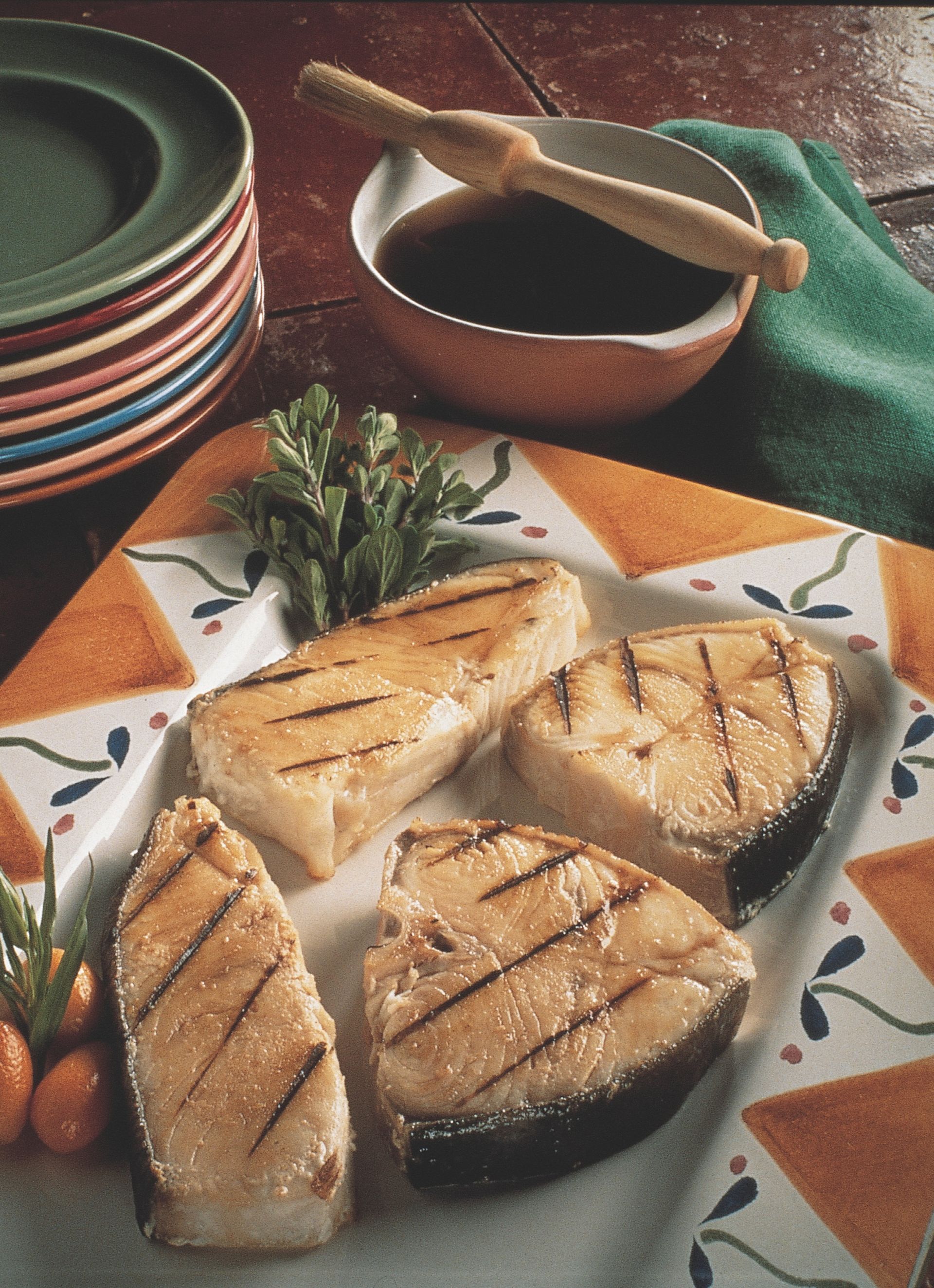 A plate of grilled fish with a bowl of sauce in the background
