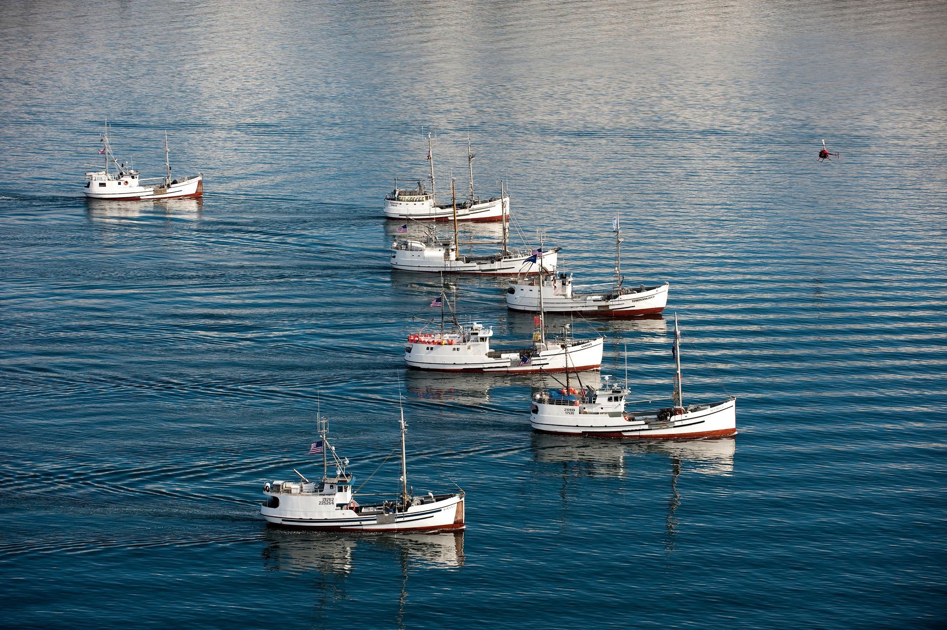 A row of boats are floating on top of a body of water.