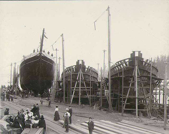 A black and white photo of three boats being built