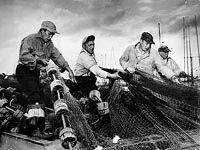 A group of men are working on a fishing net on a boat.