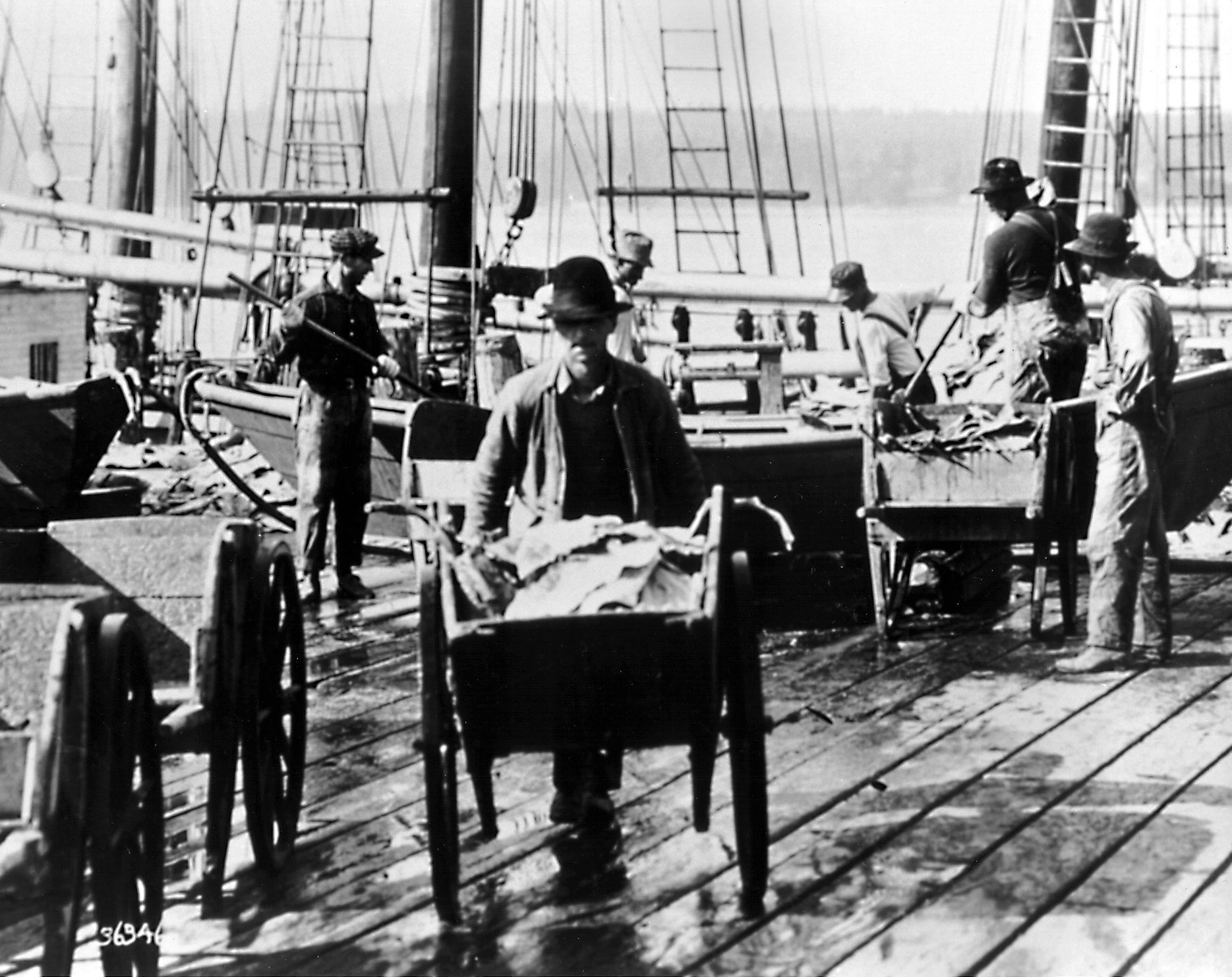 A black and white photo of a man pushing a cart
