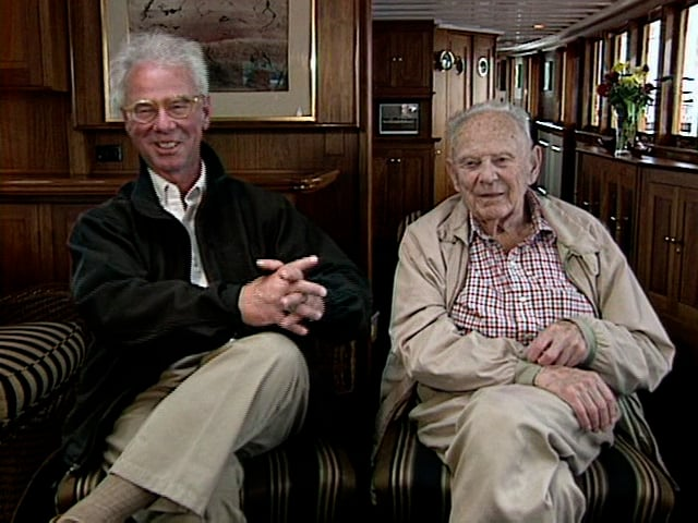 Two older men are sitting next to each other in chairs