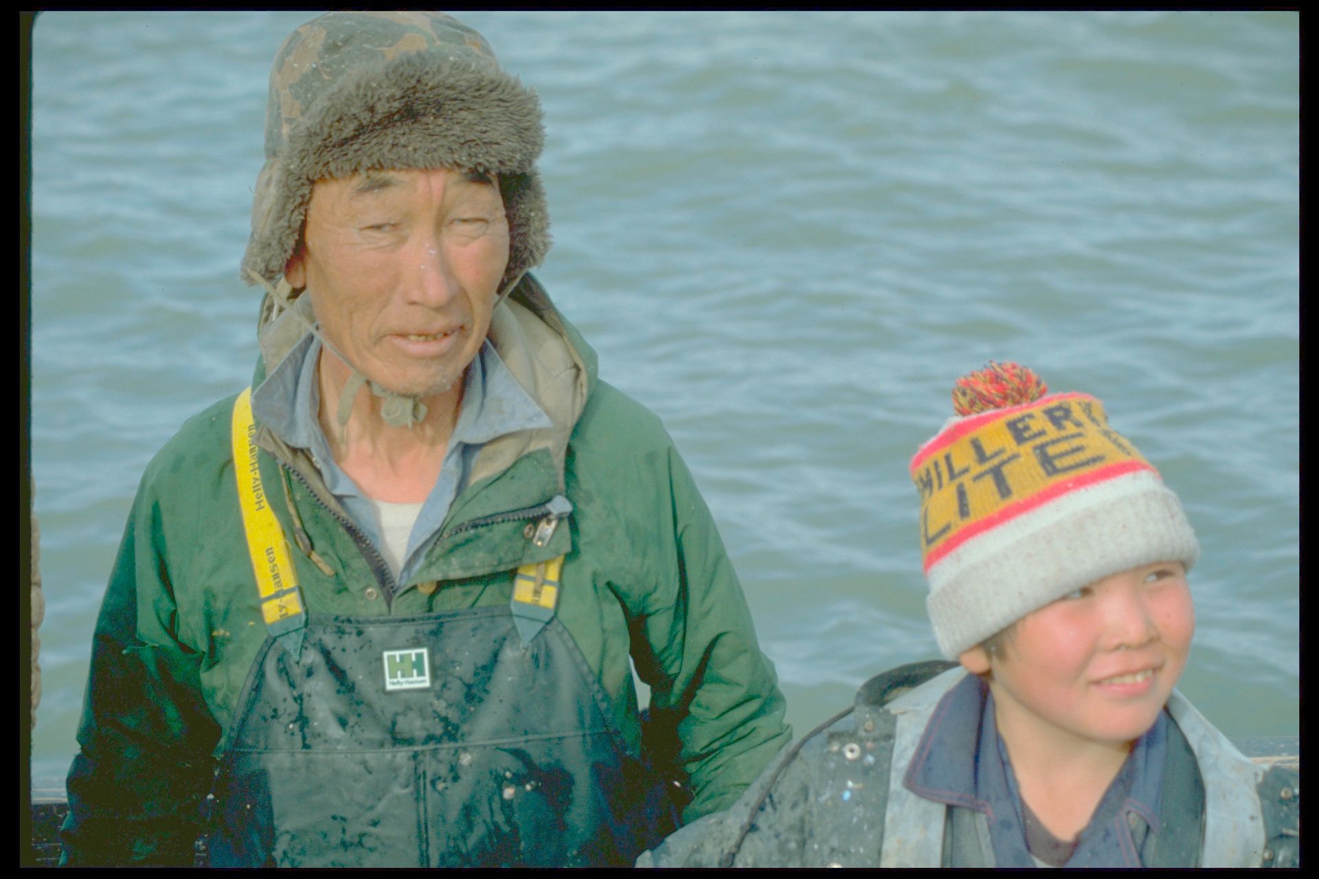 A man and a boy are standing next to each other and the boy is wearing a hat that says miller lite