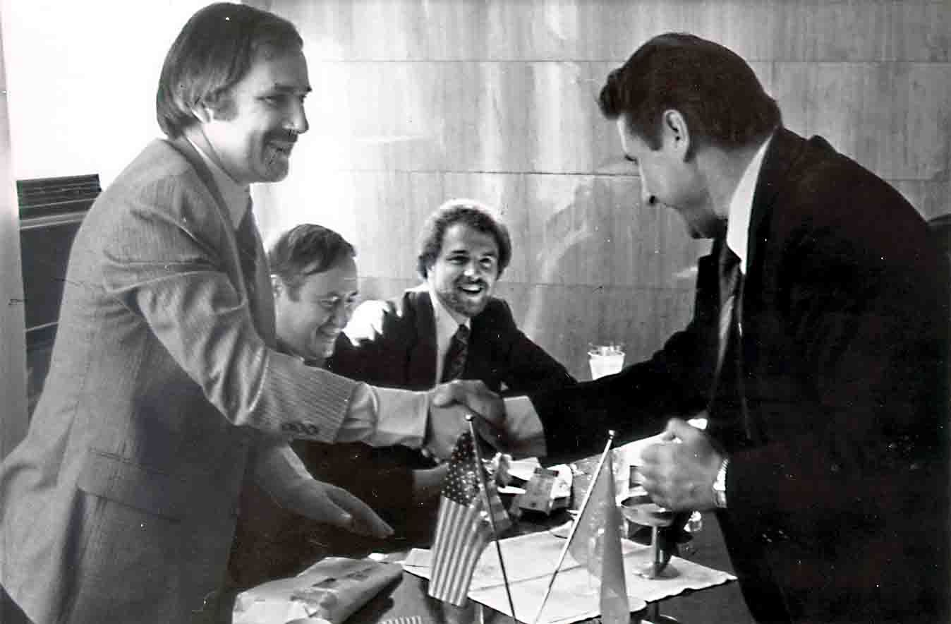 A group of men are shaking hands in a black and white photo