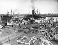A black and white photo of a shipyard with boats being built.
