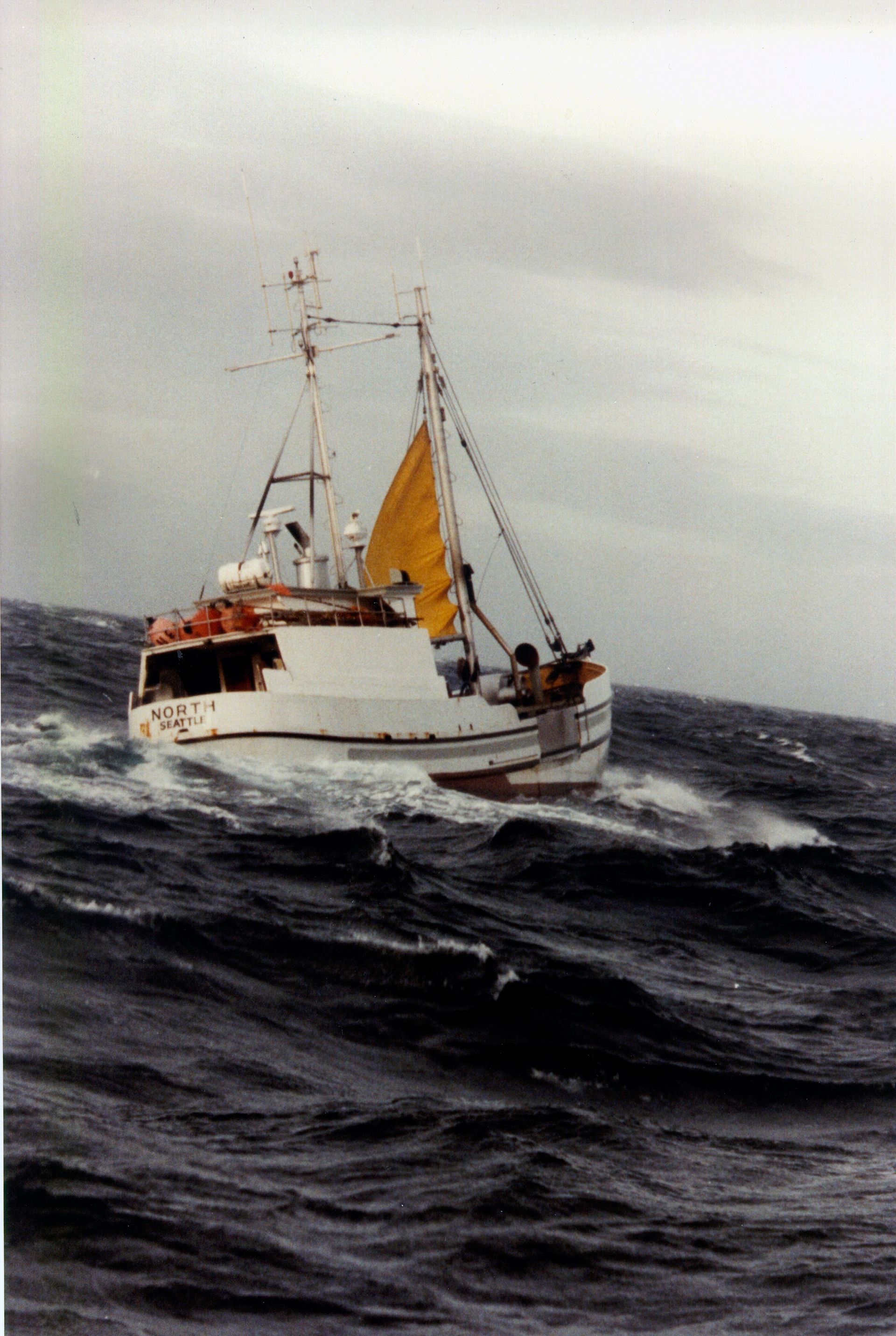 A boat with a yellow sail is floating in the ocean
