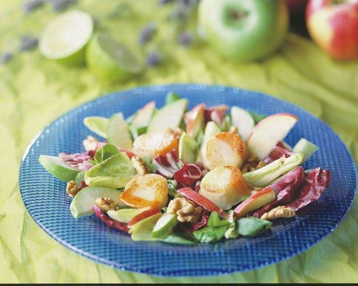 A salad with apples and walnuts on a blue plate