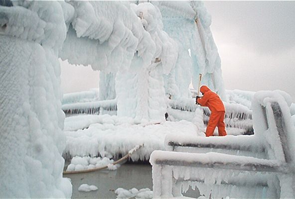 A man in an orange suit is standing in a snowy area.