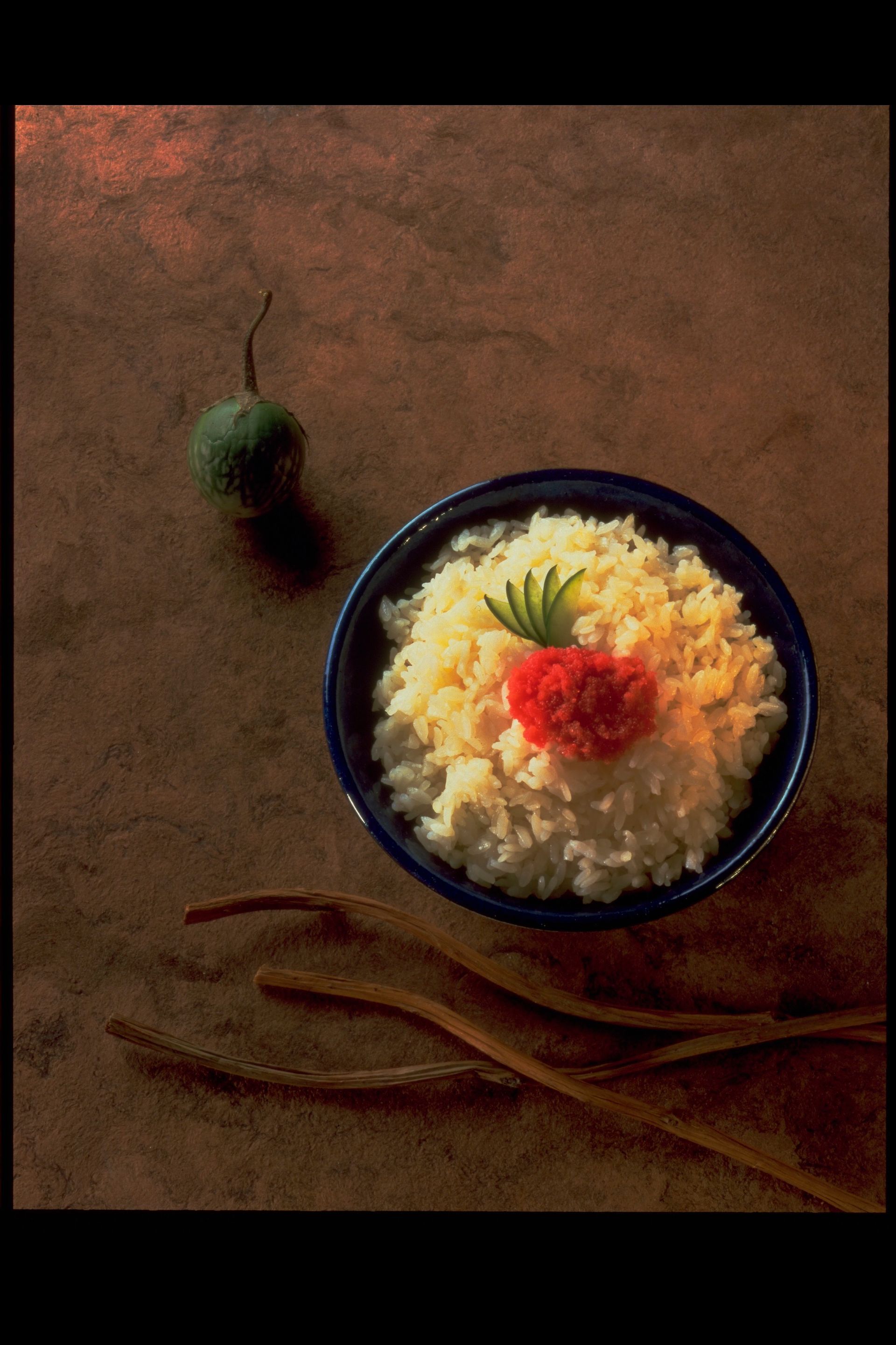 A bowl of rice with a red flower on top