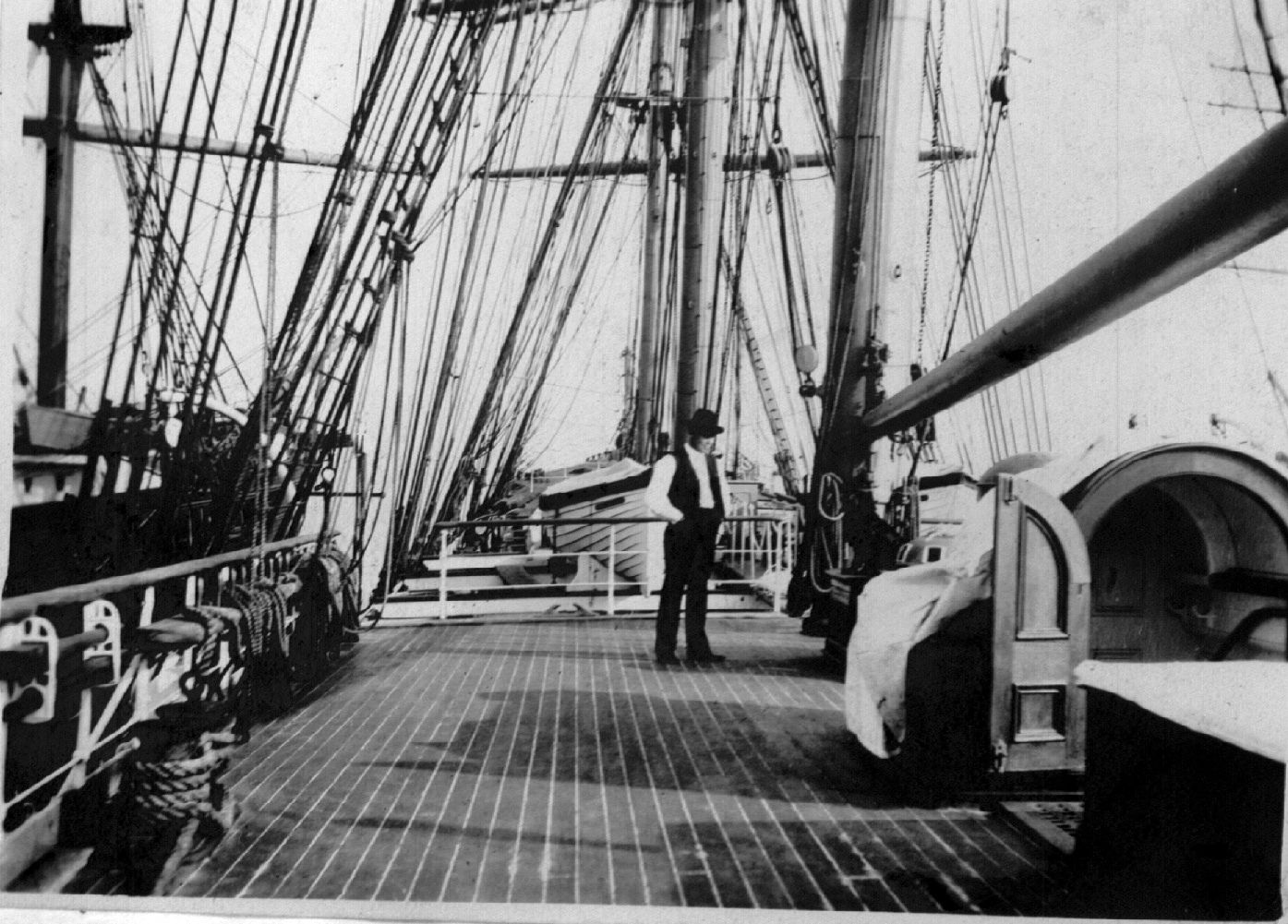 A black and white photo of a man standing on the deck of a ship