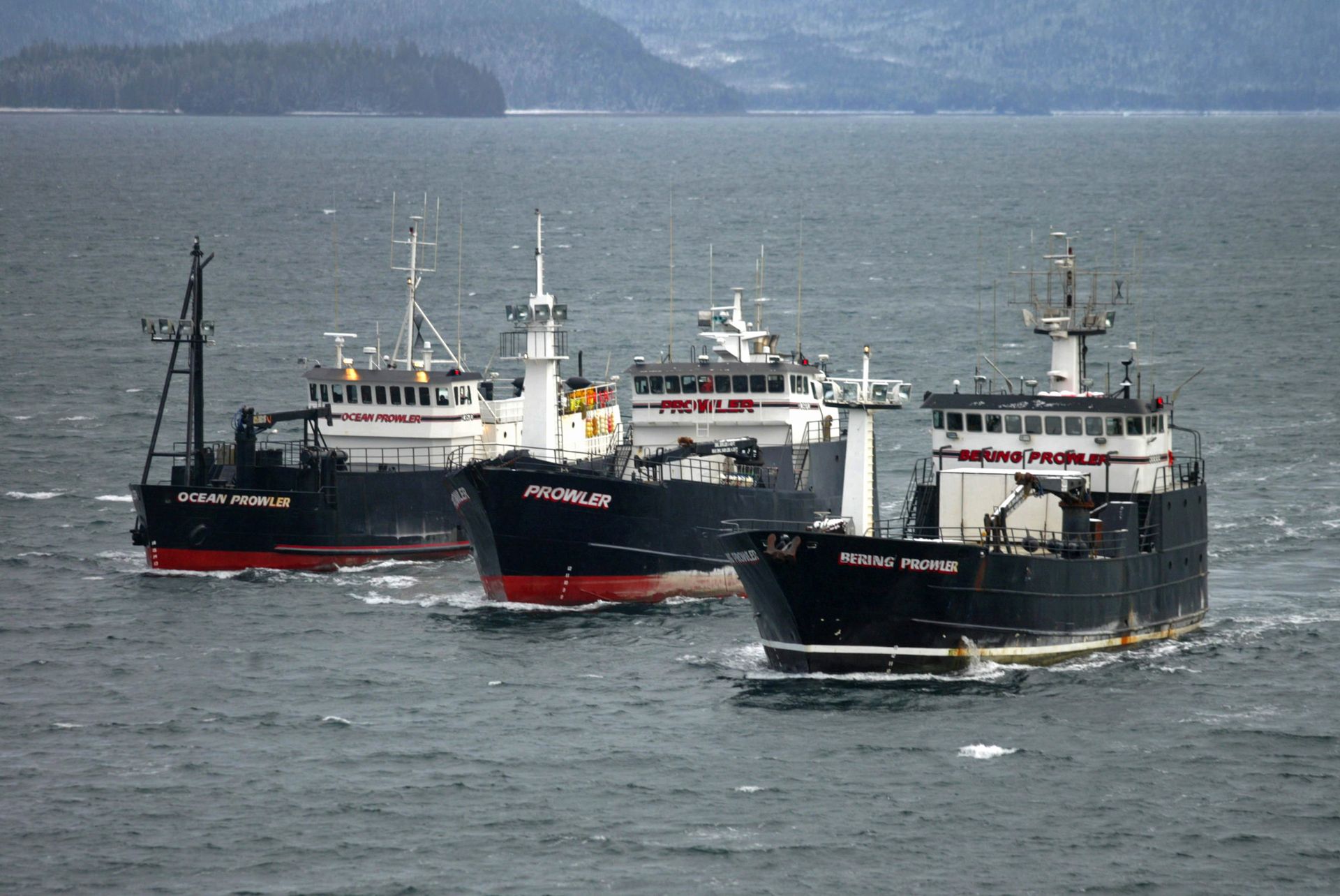 Three boats in the ocean one of which has the word pacific on the side