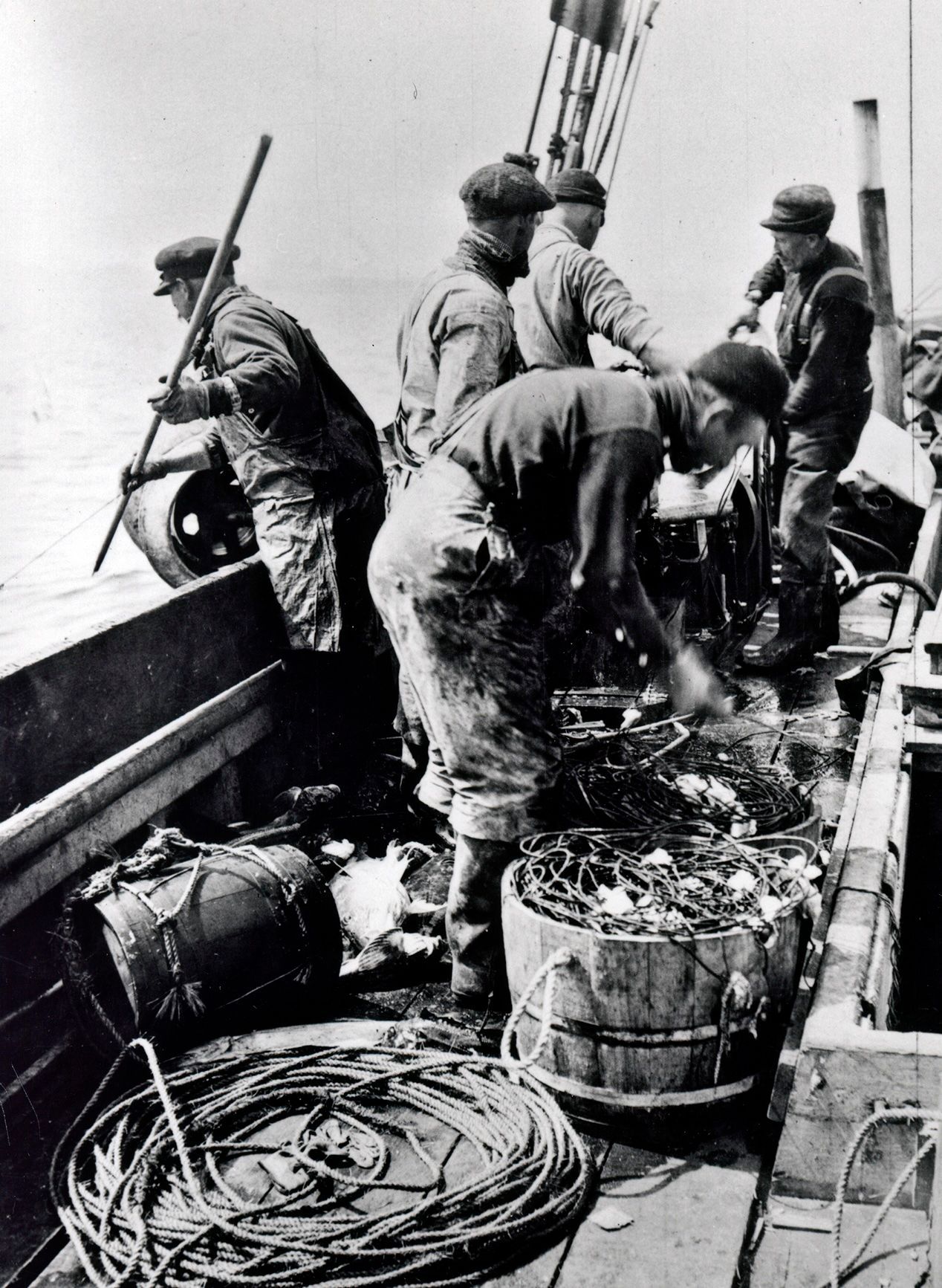 A black and white photo of a group of men working on a boat