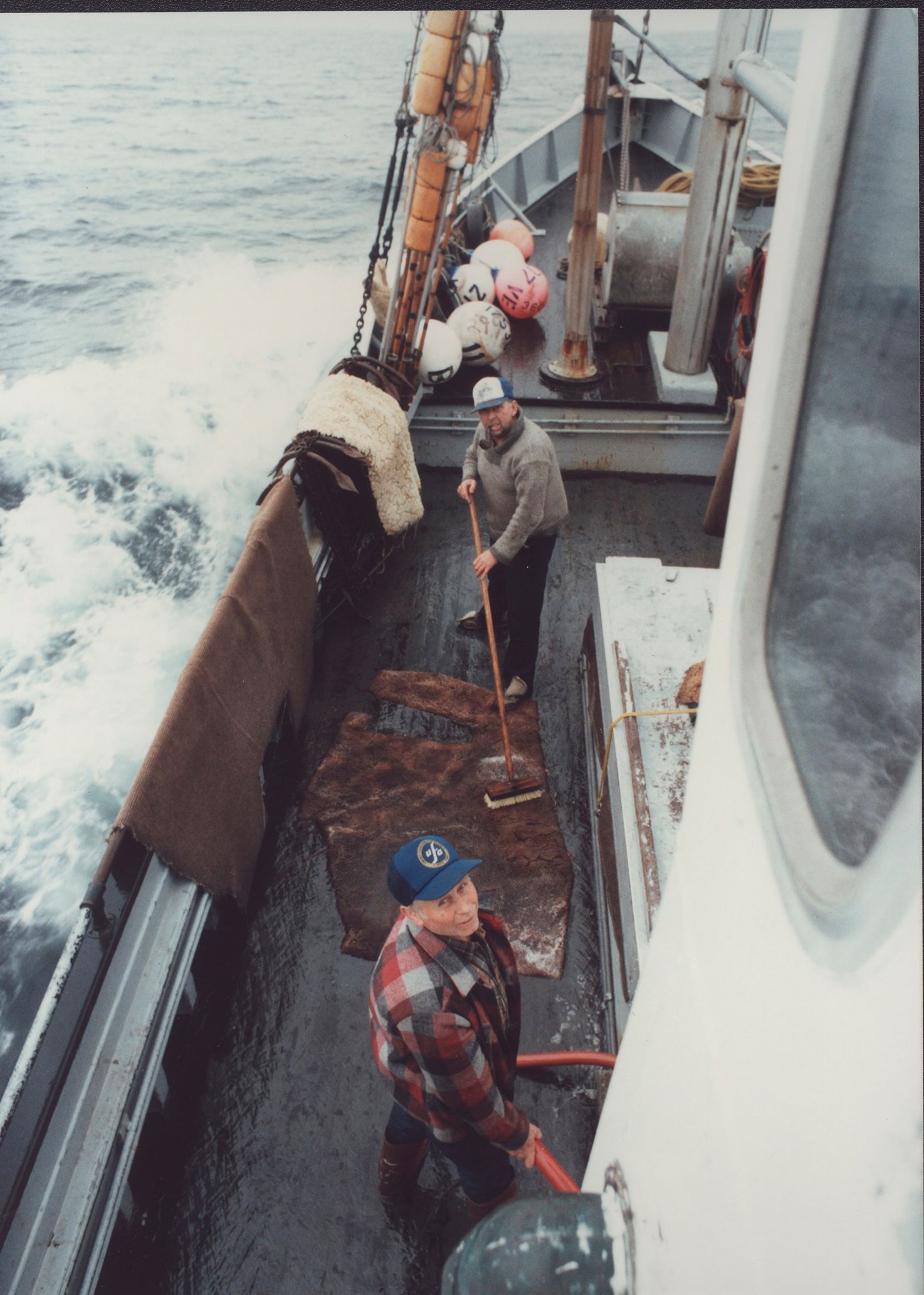 A man standing on a boat holding a shovel