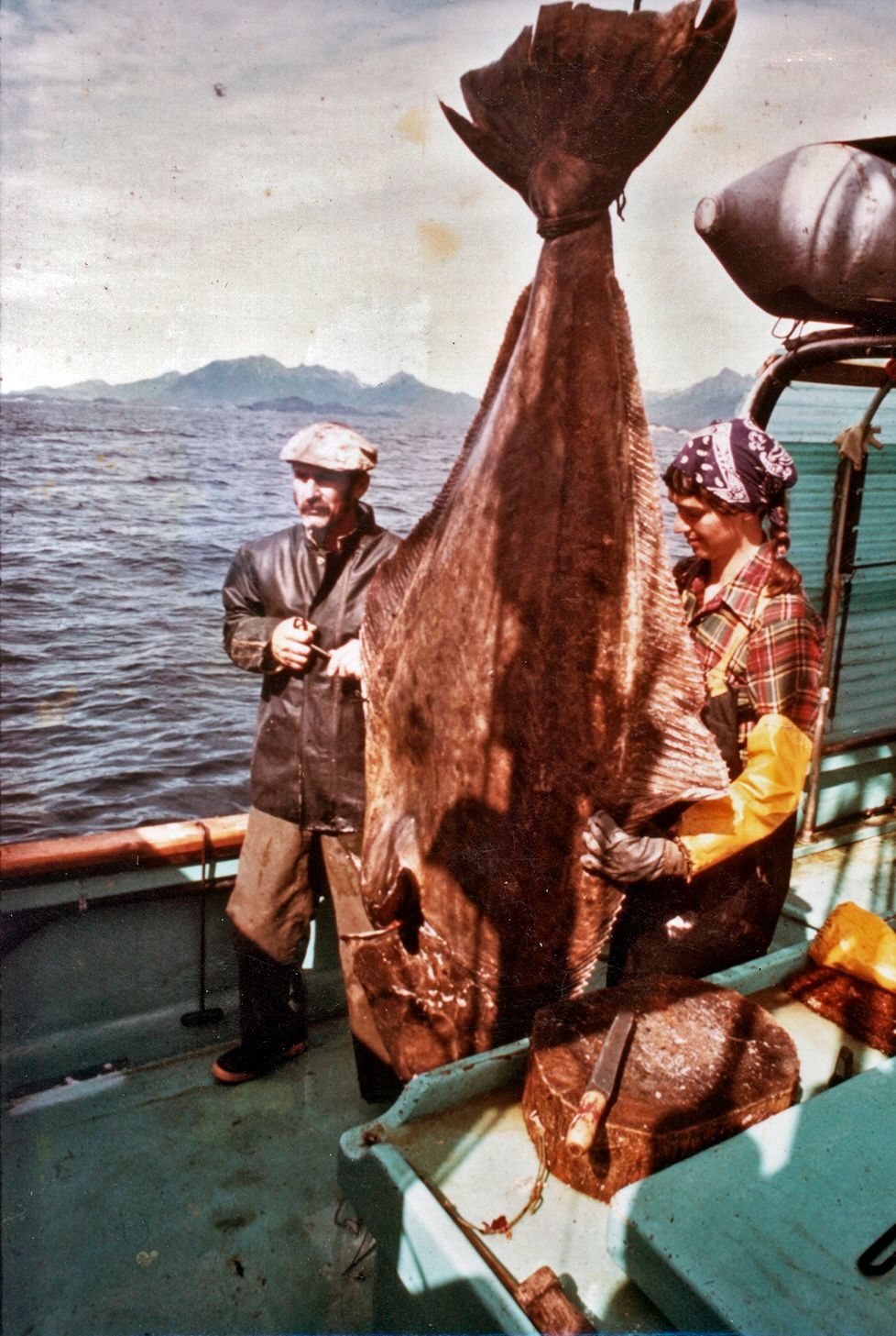 A man and a woman on a boat holding a large fish